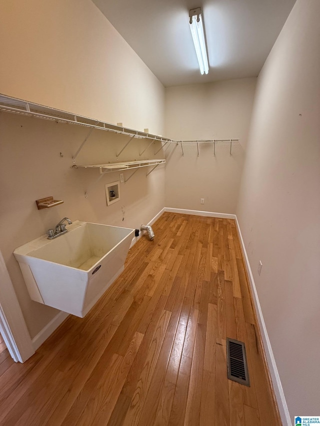 washroom with hardwood / wood-style flooring, hookup for a washing machine, and sink