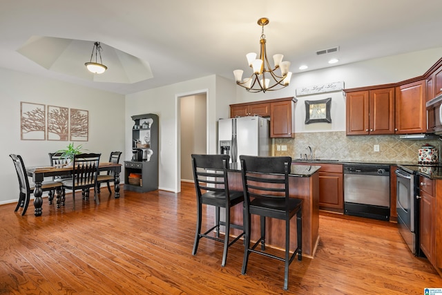 kitchen featuring sink, stainless steel appliances, a notable chandelier, a breakfast bar, and a kitchen island