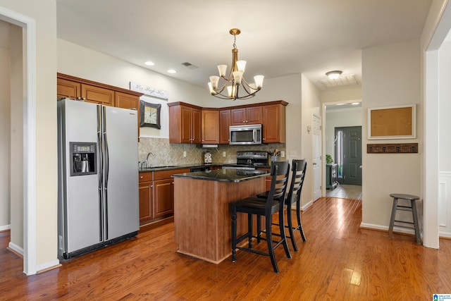 kitchen with a kitchen bar, a center island, stainless steel appliances, and an inviting chandelier