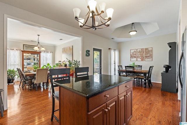 kitchen with decorative light fixtures, a center island, dark stone countertops, and a wealth of natural light