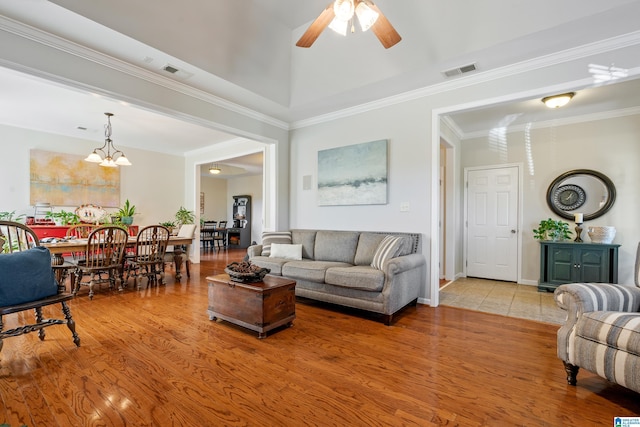 living room featuring wood-type flooring, ceiling fan with notable chandelier, and ornamental molding