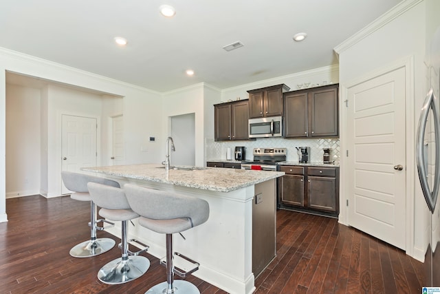 kitchen featuring sink, light stone countertops, an island with sink, tasteful backsplash, and stainless steel appliances