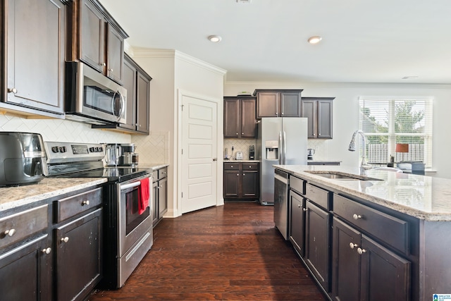 kitchen featuring light stone countertops, dark hardwood / wood-style flooring, stainless steel appliances, sink, and an island with sink