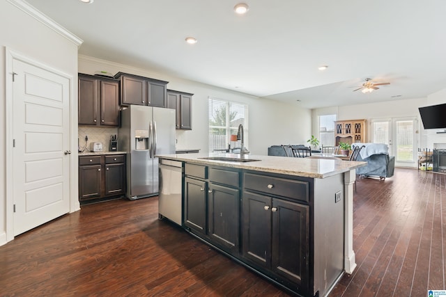 kitchen featuring backsplash, a center island with sink, sink, ceiling fan, and appliances with stainless steel finishes