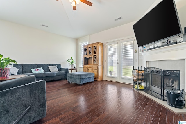 living room featuring a tile fireplace, ceiling fan, and dark hardwood / wood-style flooring