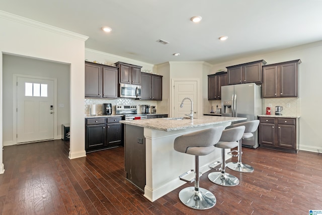 kitchen with dark brown cabinetry, sink, stainless steel appliances, a kitchen breakfast bar, and a kitchen island with sink