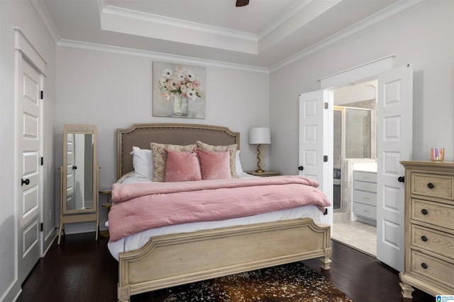 bedroom featuring a tray ceiling, connected bathroom, ceiling fan, and dark wood-type flooring