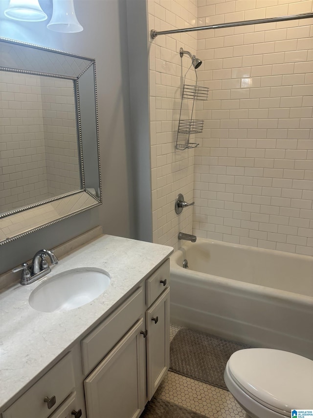 full bathroom featuring tile patterned flooring, vanity, tiled shower / bath combo, and toilet