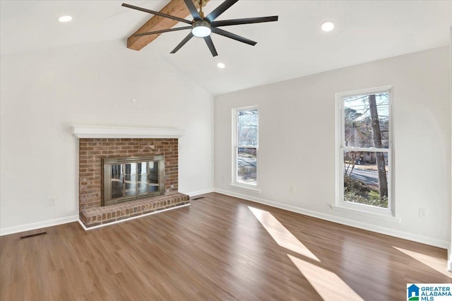 unfurnished living room featuring vaulted ceiling with beams, dark hardwood / wood-style flooring, a wealth of natural light, and a brick fireplace