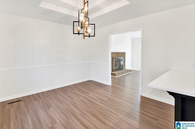 unfurnished dining area with dark hardwood / wood-style flooring, a fireplace, and a chandelier