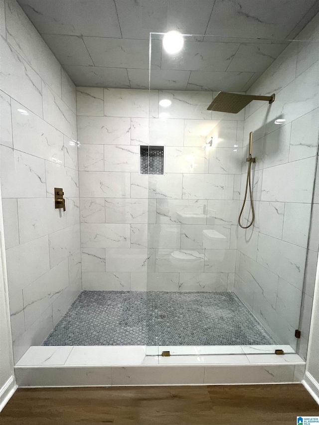 bathroom with a tile shower and hardwood / wood-style flooring