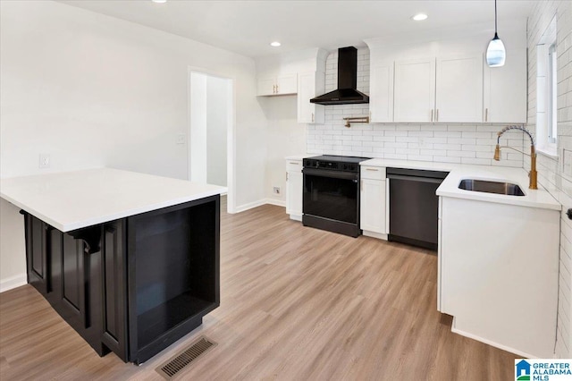 kitchen with white cabinetry, dishwasher, hanging light fixtures, wall chimney range hood, and black / electric stove