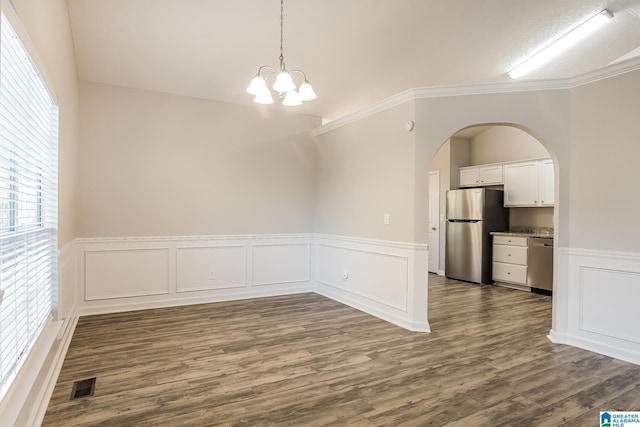 unfurnished dining area featuring crown molding, dark hardwood / wood-style floors, and an inviting chandelier