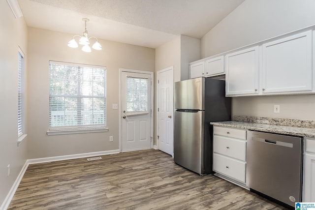 kitchen featuring light stone countertops, white cabinets, stainless steel appliances, and a notable chandelier