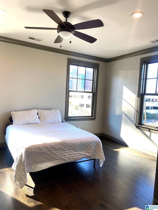 bedroom with dark hardwood / wood-style floors, ceiling fan, and ornamental molding