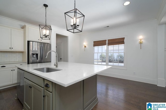 kitchen with white cabinetry, sink, stainless steel appliances, an island with sink, and decorative backsplash