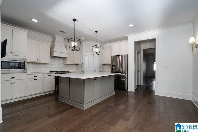 kitchen with appliances with stainless steel finishes, custom exhaust hood, sink, a center island with sink, and white cabinetry