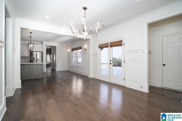 unfurnished dining area featuring dark hardwood / wood-style floors, ornamental molding, sink, and an inviting chandelier