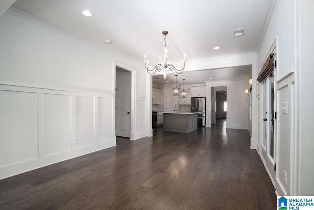 interior space featuring sink, ornamental molding, dark wood-type flooring, and an inviting chandelier