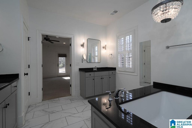 bathroom featuring plenty of natural light, vanity, ceiling fan with notable chandelier, and a washtub