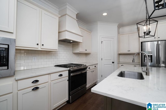 kitchen with custom exhaust hood, sink, stainless steel fridge, black gas range oven, and decorative light fixtures