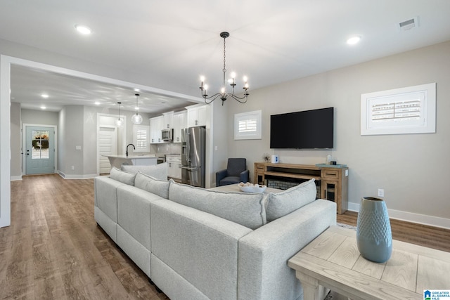 living room featuring a chandelier, light hardwood / wood-style floors, and sink