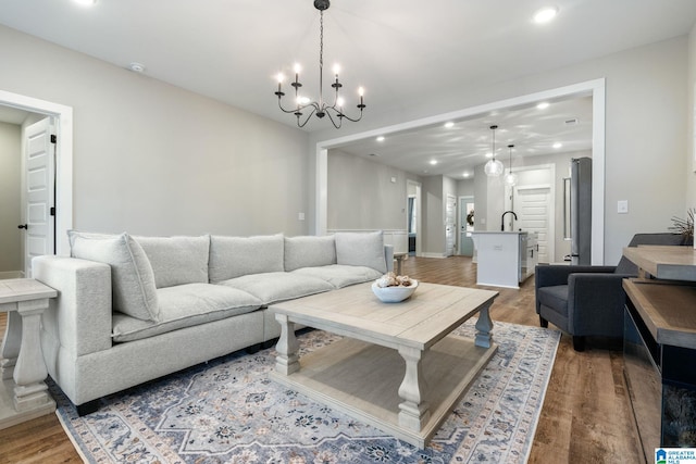 living room with sink, an inviting chandelier, and hardwood / wood-style flooring