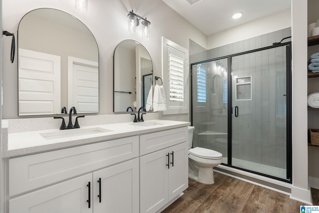 bathroom with wood-type flooring, vanity, toilet, and a shower with door