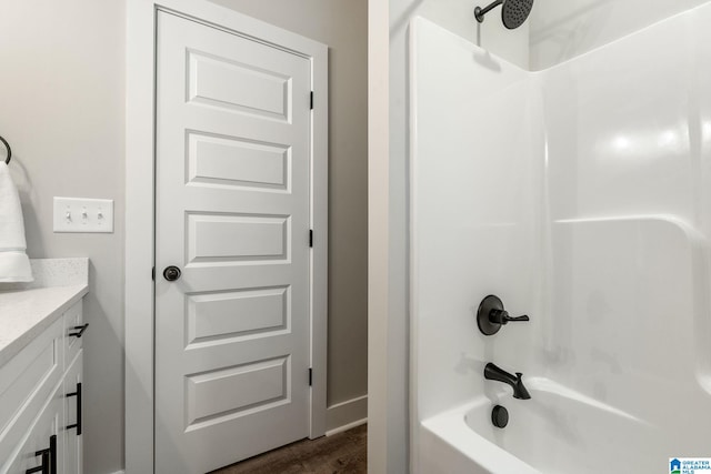 bathroom with hardwood / wood-style flooring, vanity, and bathing tub / shower combination