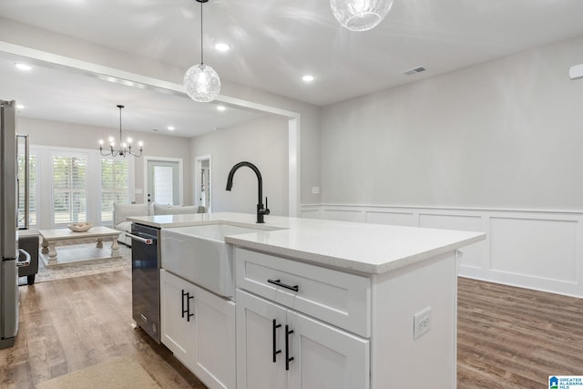 kitchen with white cabinetry, sink, wood-type flooring, decorative light fixtures, and a center island with sink