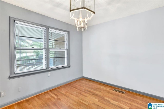 spare room with wood-type flooring and a notable chandelier