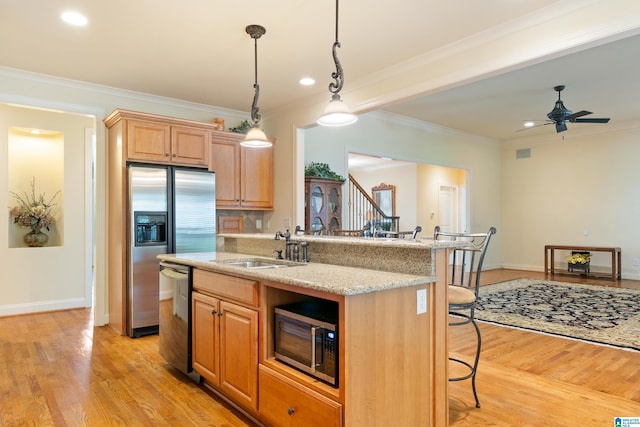 kitchen with sink, a kitchen bar, ornamental molding, and stainless steel appliances