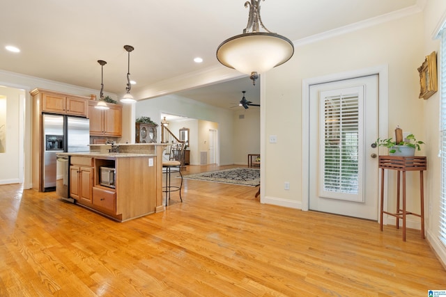 kitchen featuring stainless steel fridge, a breakfast bar, crown molding, decorative light fixtures, and a center island with sink