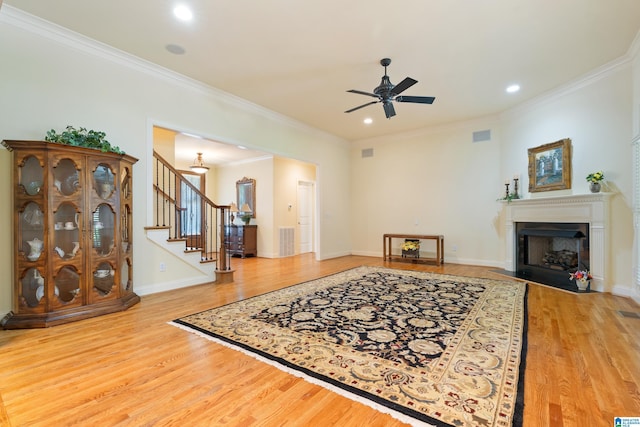 living room with hardwood / wood-style flooring, ceiling fan, and crown molding