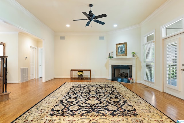 living room with light wood-type flooring, ceiling fan, and ornamental molding