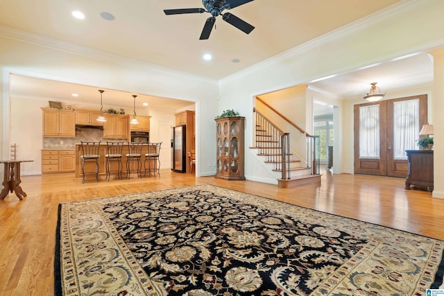 living room with ceiling fan, french doors, ornamental molding, and light wood-type flooring