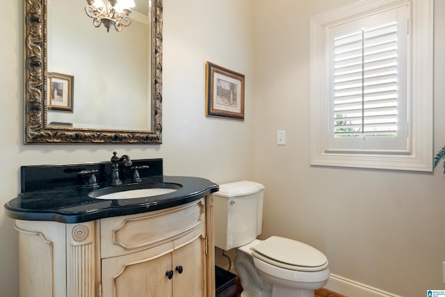 bathroom featuring toilet, vanity, and a notable chandelier