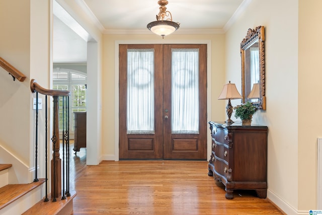 foyer with light hardwood / wood-style floors, ornamental molding, and french doors