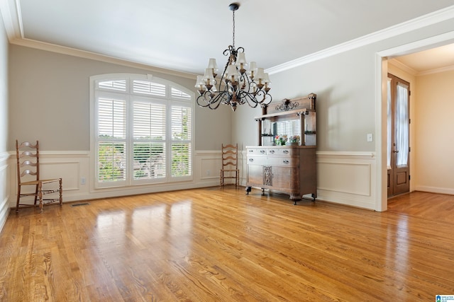 unfurnished dining area with a chandelier, hardwood / wood-style floors, and ornamental molding