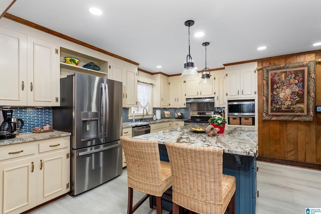 kitchen with pendant lighting, sink, light stone countertops, a kitchen island, and stainless steel appliances