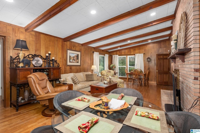 dining room with vaulted ceiling with beams, wood walls, a fireplace, and light hardwood / wood-style floors