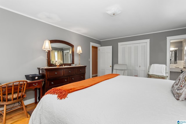 bedroom with hardwood / wood-style flooring, a closet, ornamental molding, and ensuite bath