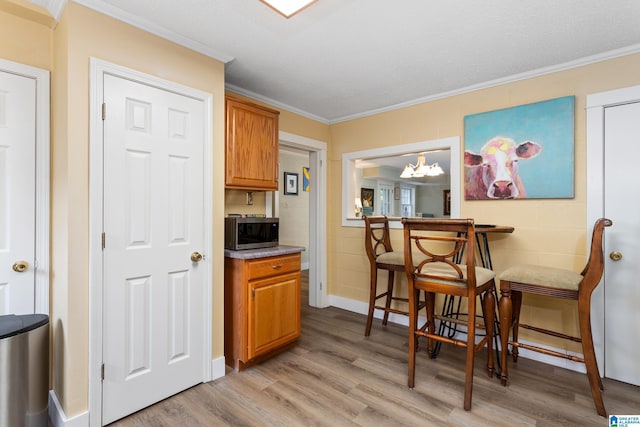 kitchen with crown molding, light wood-type flooring, a textured ceiling, and an inviting chandelier