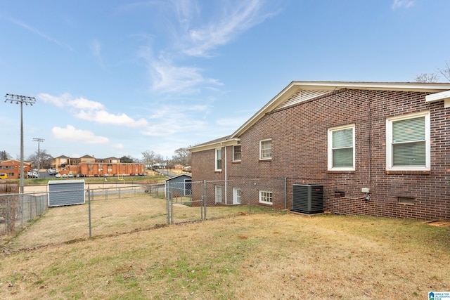 rear view of house featuring cooling unit and a lawn