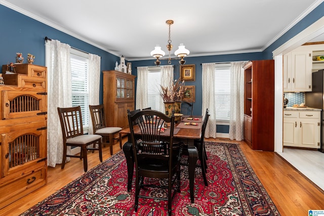 dining space featuring light hardwood / wood-style flooring, an inviting chandelier, plenty of natural light, and crown molding