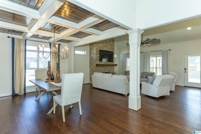 dining area with ornate columns, coffered ceiling, a brick fireplace, beamed ceiling, and ceiling fan with notable chandelier