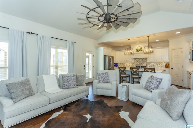 living room featuring an inviting chandelier, dark wood-type flooring, and vaulted ceiling