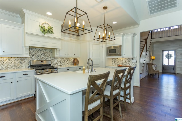 kitchen featuring white cabinetry, a kitchen breakfast bar, decorative light fixtures, a kitchen island with sink, and appliances with stainless steel finishes