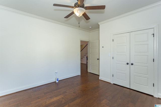 unfurnished bedroom with ceiling fan, dark wood-type flooring, crown molding, and a closet