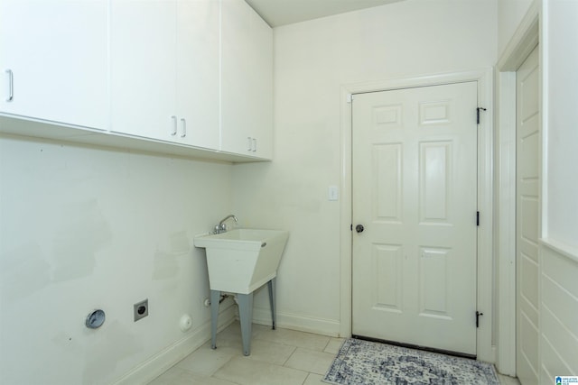 washroom with hookup for an electric dryer, light tile patterned flooring, and cabinets